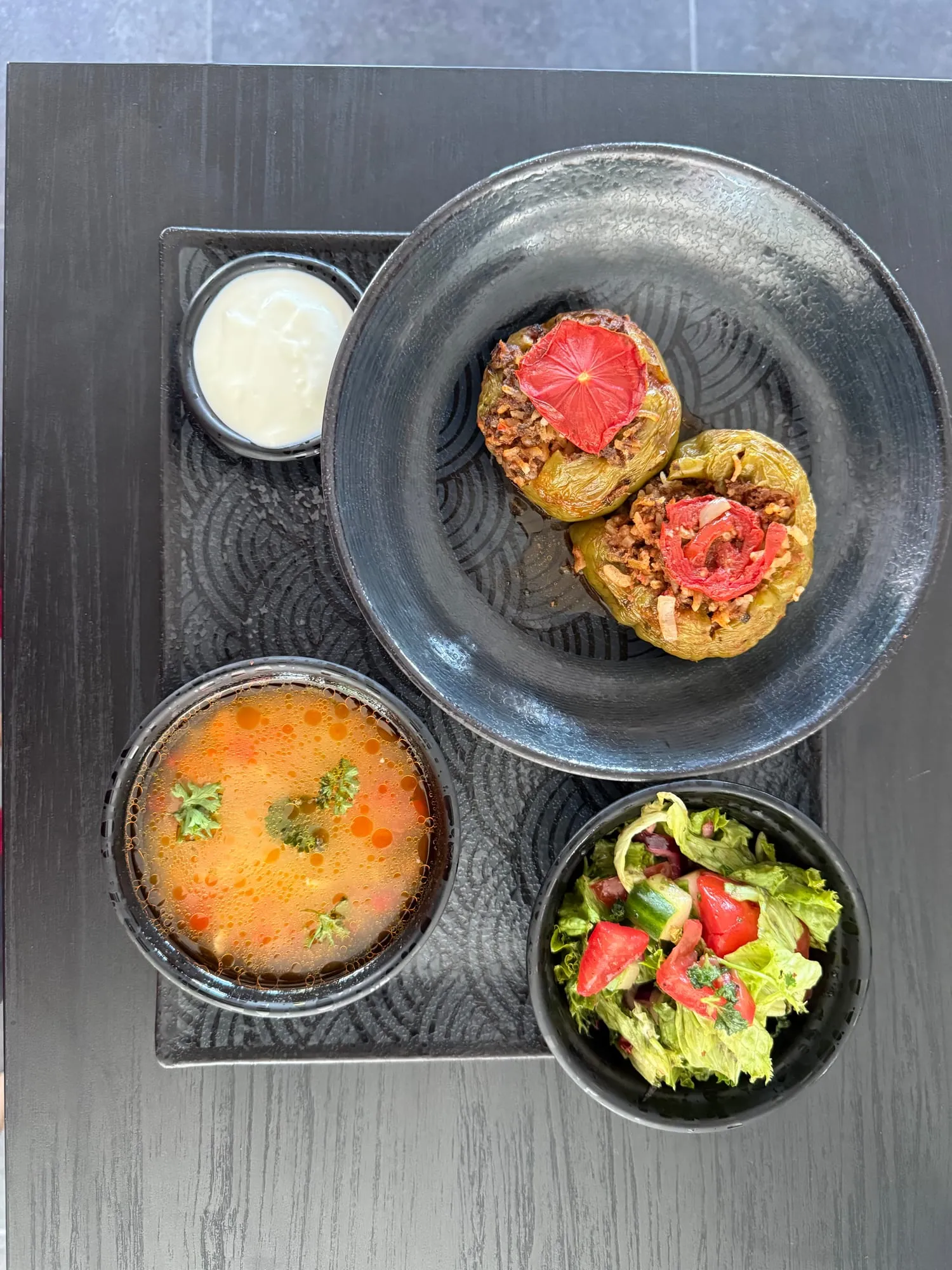 Gefüllte Paprika mit Salat und Suppe auf dunklem Teller